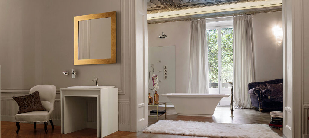 Luxurious bathroom with a freestanding bathtub, elegant armchair, and large mirror. Soft lighting and large windows create an inviting, serene atmosphere.