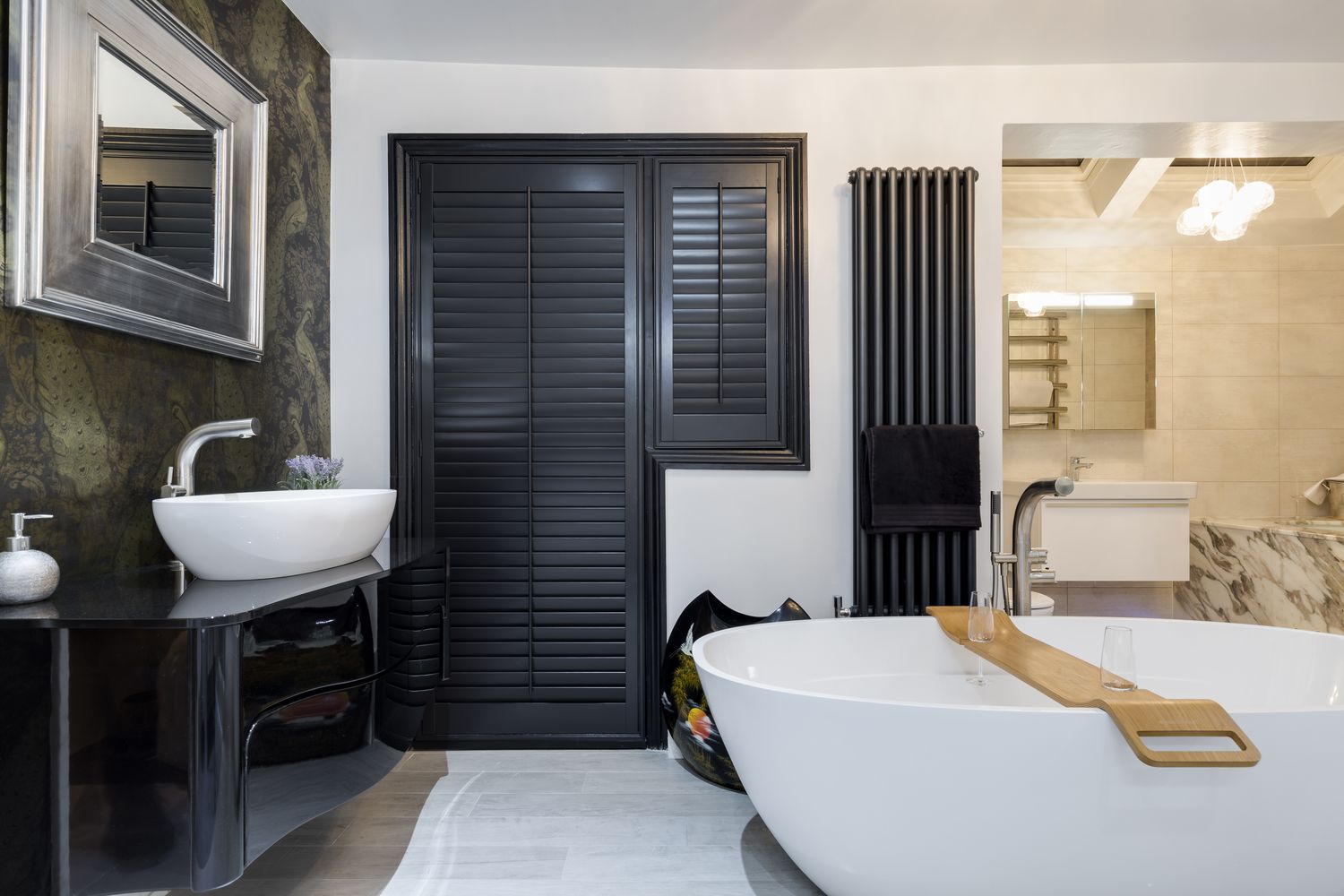 Modern bathroom with black shutters, stylish mirror, elegant bathtub, and contemporary sink. Warm lighting enhances the sophisticated interior design elements.