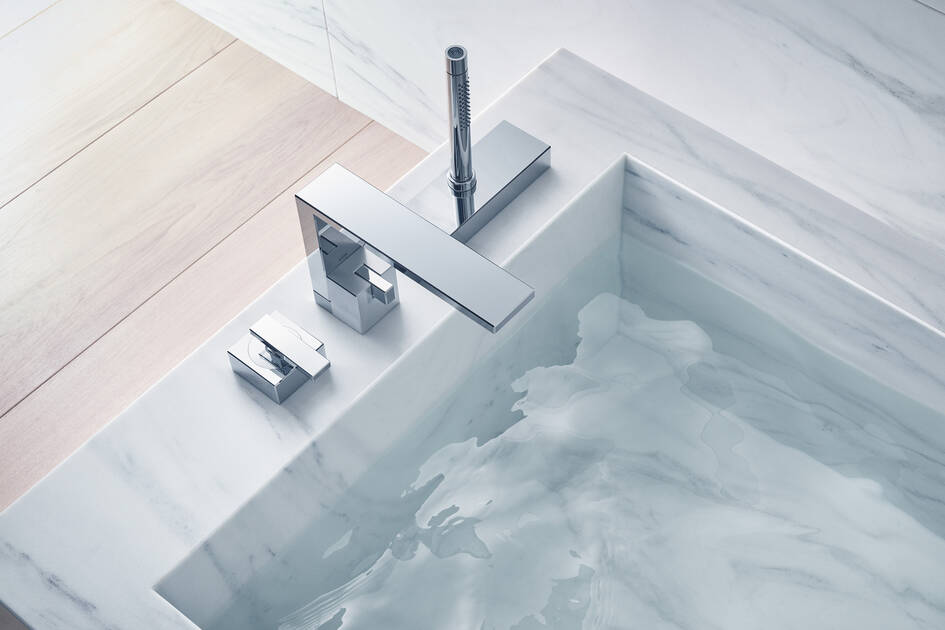 A modern bathroom sink with a sleek, chrome faucet and minimalistic design, set on a marble countertop, partially filled with clear water.