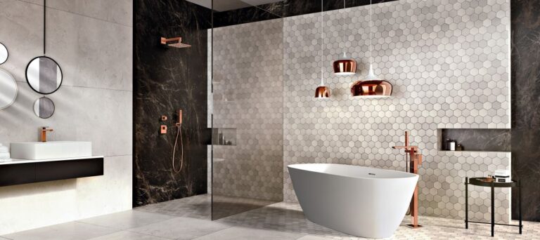 Modern bathroom with a white freestanding tub, hexagonal tile wall, round mirrors, and copper fixtures. Minimalist design, featuring elegant lighting and sleek surfaces.
