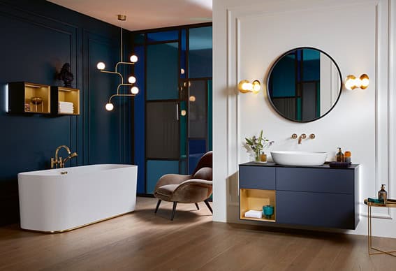 Modern bathroom with freestanding tub, stylish lighting, and a vanity with round mirror. Sleek blue and white decor complements warm wood flooring.
