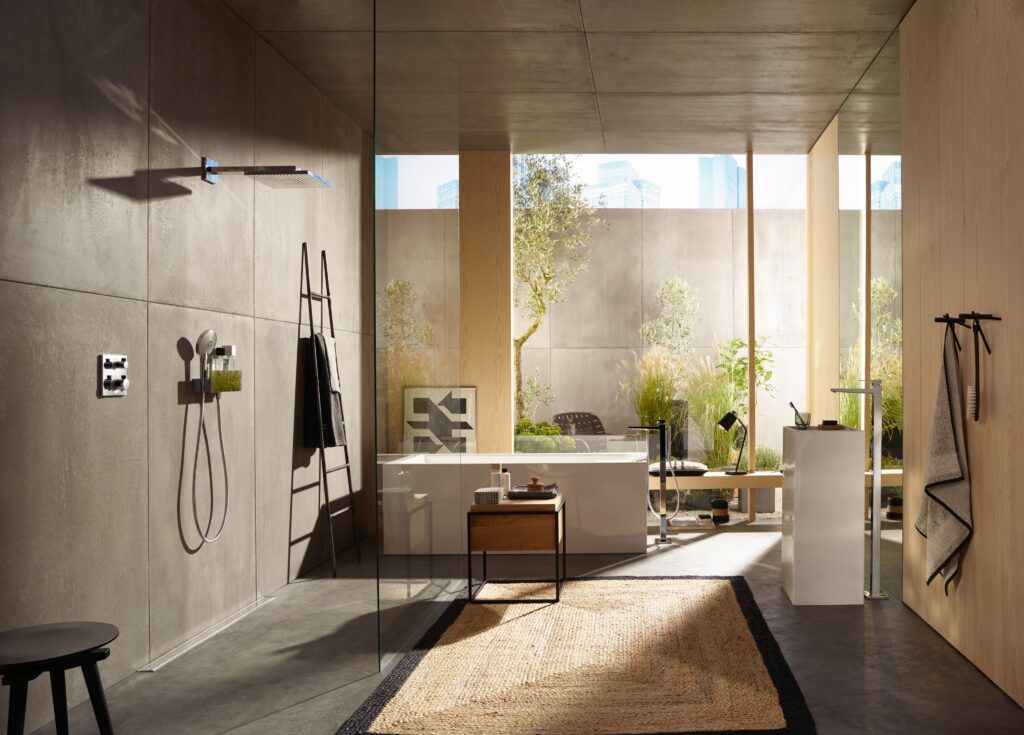 Modern bathroom with glass walls, rain shower, and minimalist design. Sunlit garden visible outside. Neutral tones and natural materials create a serene atmosphere.