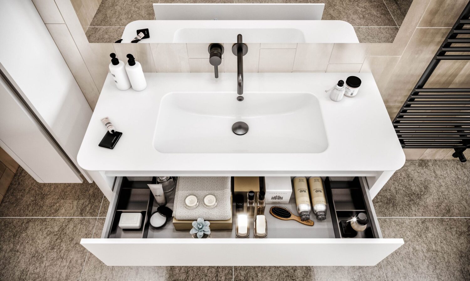 Modern bathroom with a white sink, open drawer containing toiletries, neatly organized bottles, towels, and a brush. Neutral-toned tiles and wall decor.