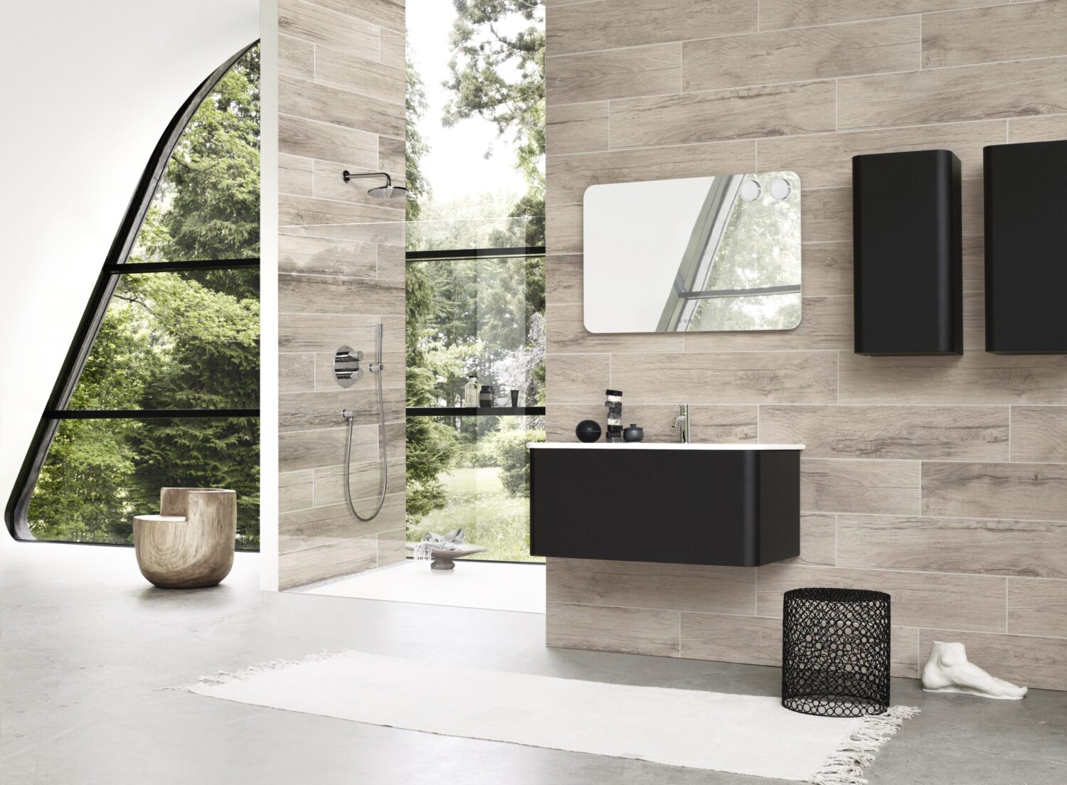 Modern bathroom with large glass window, showcasing a sleek shower, vanity, and wooden chair. Outdoor greenery visible through the window.