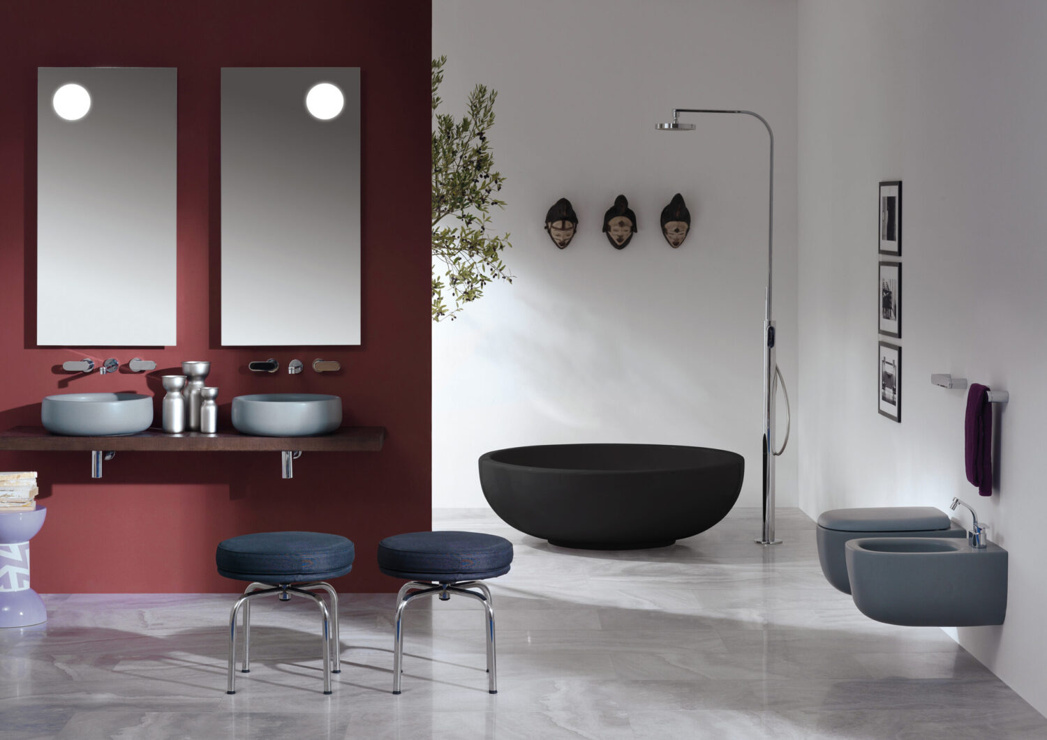 Modern bathroom with red and white walls, dual sinks, black bathtub, stools, masks, mirrors, and framed photos. Elegant, minimalist design.