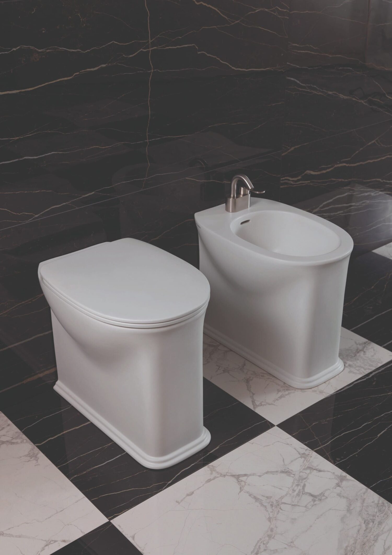 A luxurious bathroom with a modern toilet and bidet on a black marble wall and checkerboard tile floor, creating a sophisticated look.