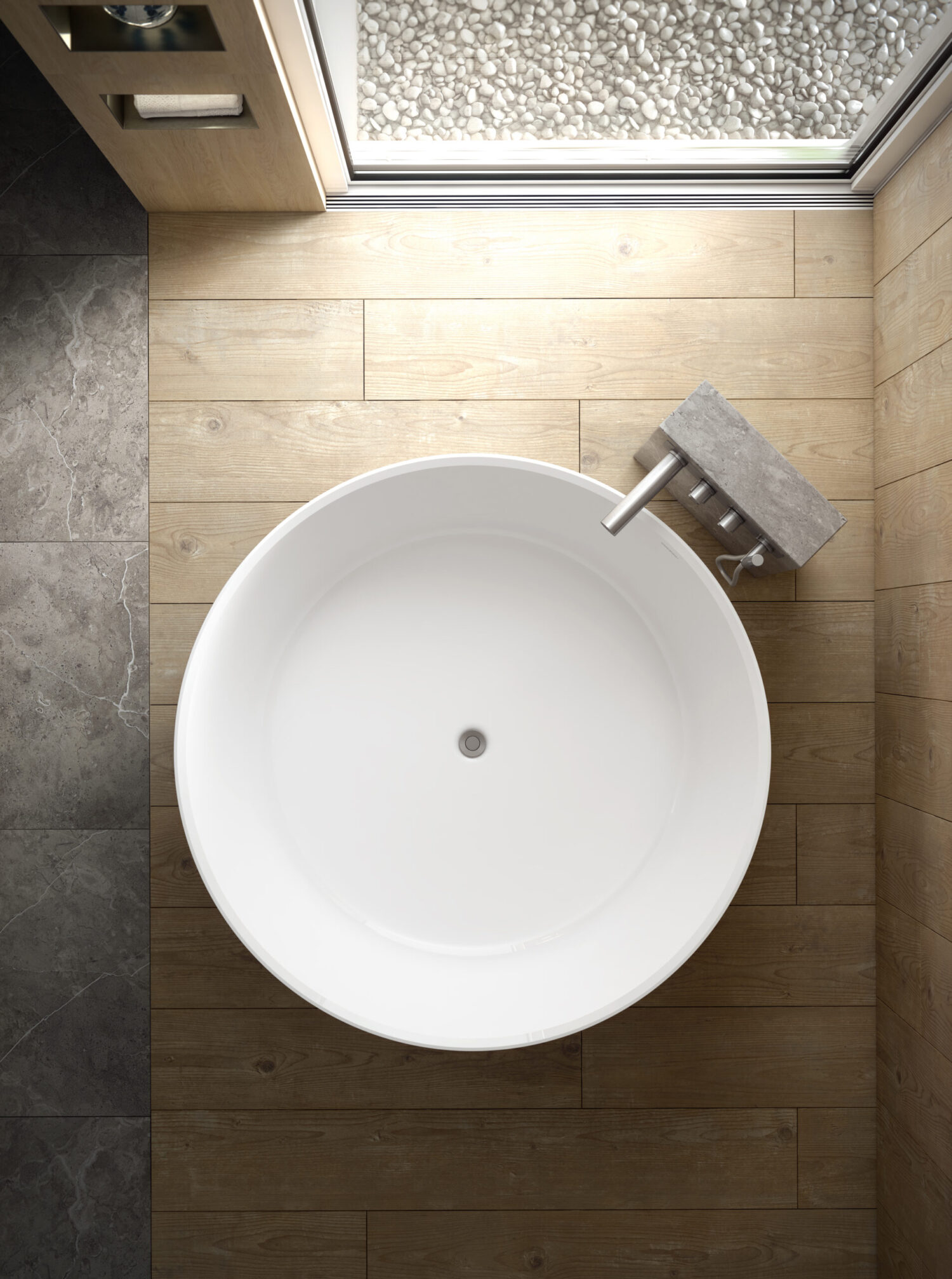 Modern bathroom with a round white bathtub, wooden flooring, and stone pebbles near a window, creating a minimalist, natural aesthetic.