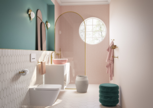 Modern bathroom with pink and mint green accents. Features a round window, pink sink, wall-mounted toilet, gold fixtures, and hexagonal tiles.