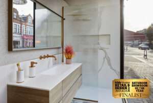 Modern bathroom showroom with marble and wood accents, visible storefronts outside. Award finalist plaque displayed on glass panel.