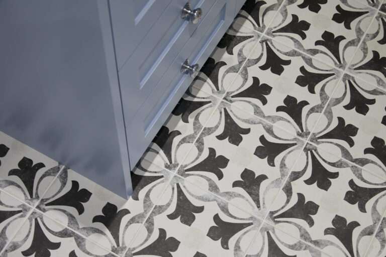The image shows a blue cabinet next to a tiled floor with a black and white floral pattern design.