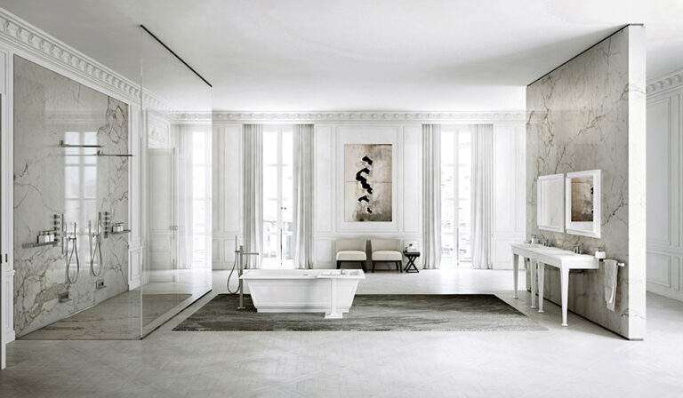 Luxurious, spacious bathroom featuring marble walls, freestanding bathtub, glass shower, dual sinks, and minimalistic decor with large windows and elegant moldings.