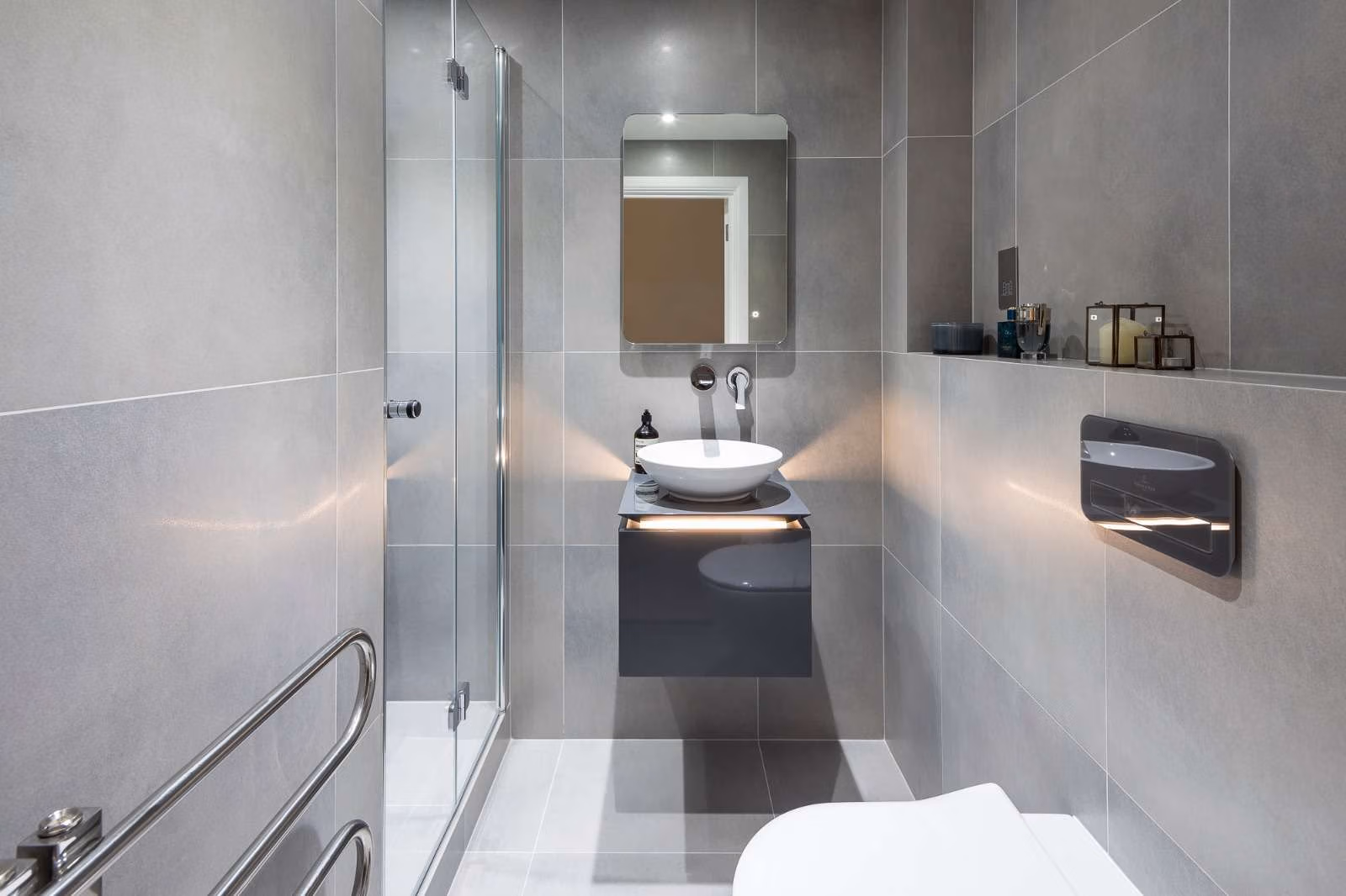 A modern bathroom featuring a sleek sink, toilet, and a glass-enclosed shower.