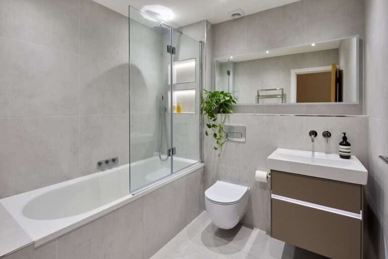 Modern grey bathroom with bathtub, wall-mounted toilet, and sleek vanity unit for contemporary bathr.