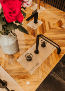Modern bathroom fixtures with black handles on a wooden surface.