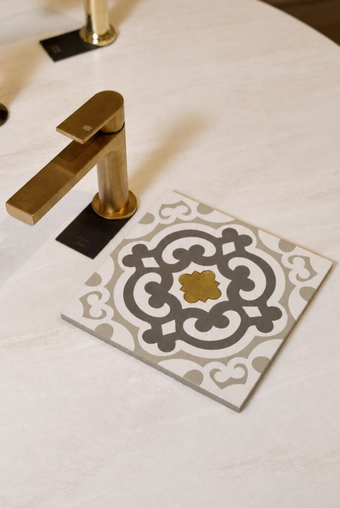 Luxury brass bathroom tap display at Kallums Bathrooms showroom, featuring elegant patterned ceramic tiles and premium bathroom design inspiration in Putney and Guildford.