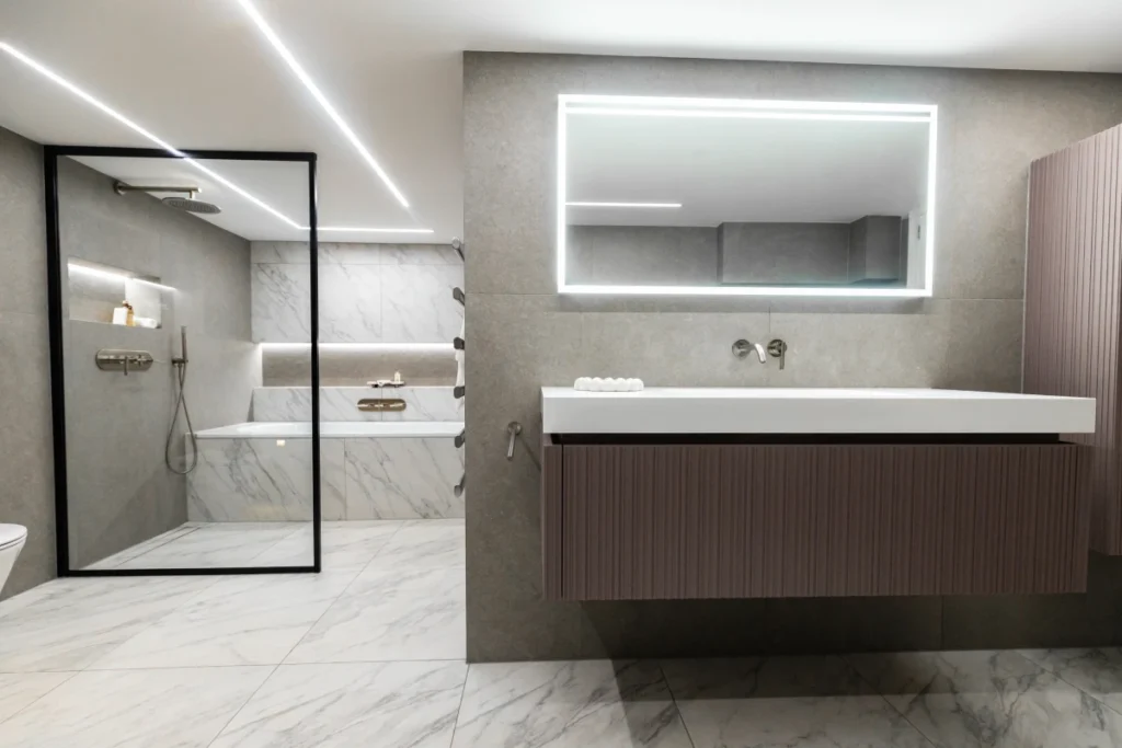 Modern bathroom with walk-in shower, floating vanity, and illuminated mirror.