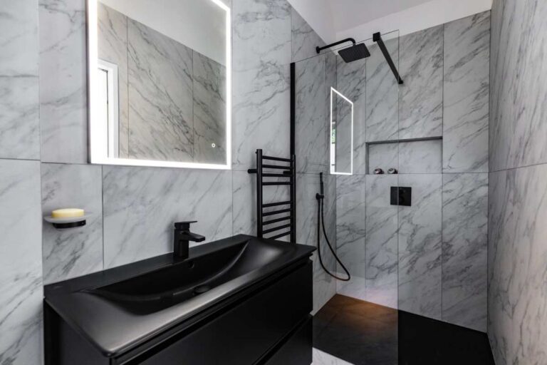 Modern black bathroom with marble walls and walk-in shower.
