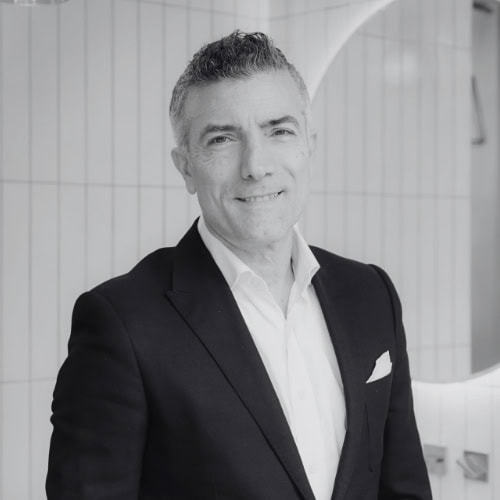 Professional man in suit smiling in modern office setting.