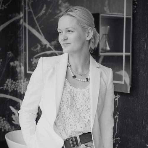 Professional woman in a white blazer and lace top in an office setting.