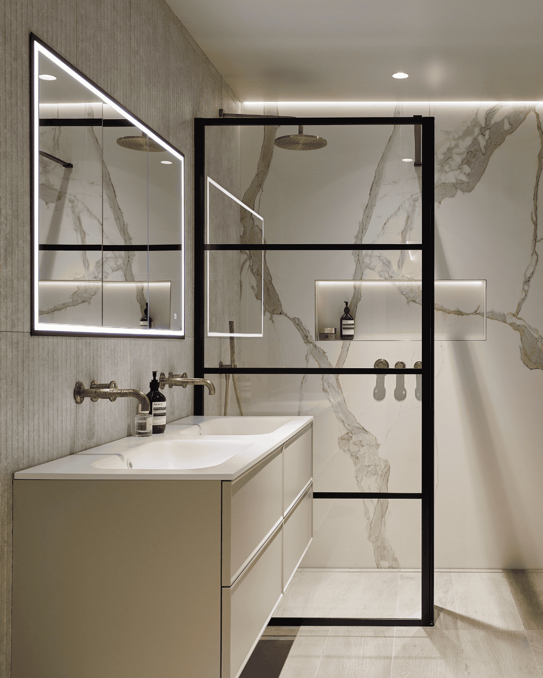Modern bathroom with marble walls, black-framed glass shower, and white vanity.