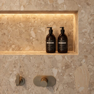 Elegant bathroom shelf with black shampoo and conditioner bottles in a modern shower.