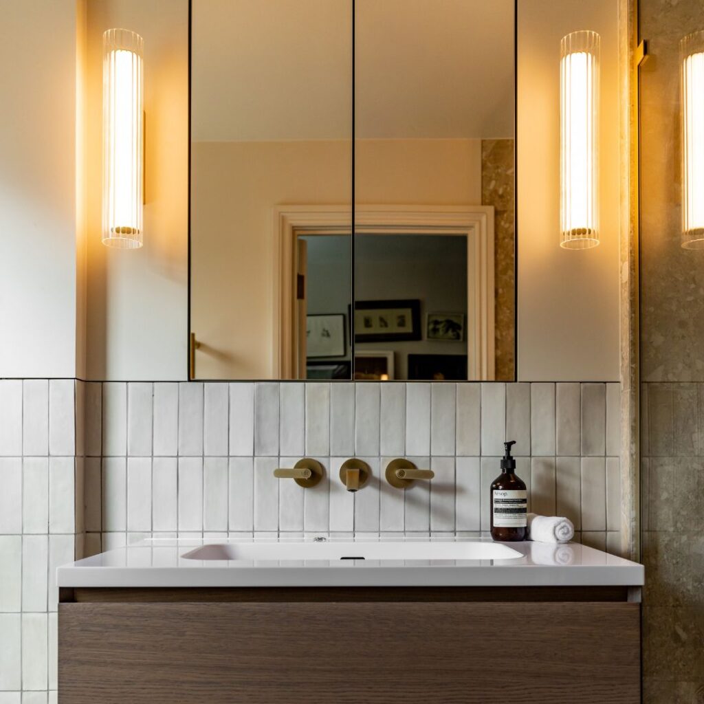 Modern bathroom with wall-mounted sink, large mirror, and warm lighting.