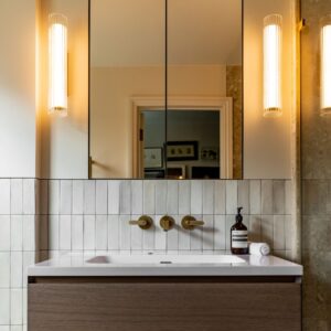 Modern bathroom with wall-mounted sink, large mirror, and warm lighting.