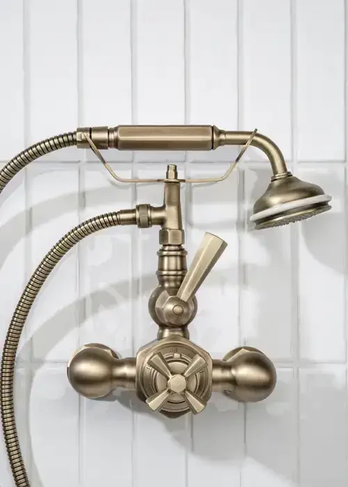 Vintage brass bathroom shower mixer tap with handheld showerhead and flexible hose.