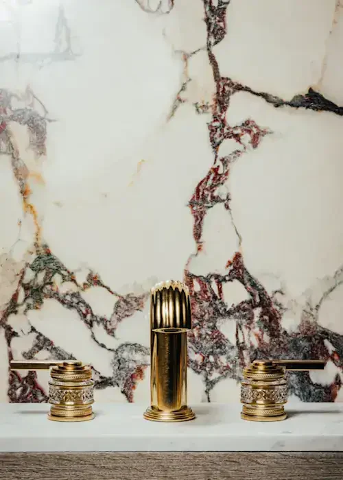 Luxury gold bathroom tap and handles with marble wall backdrop.