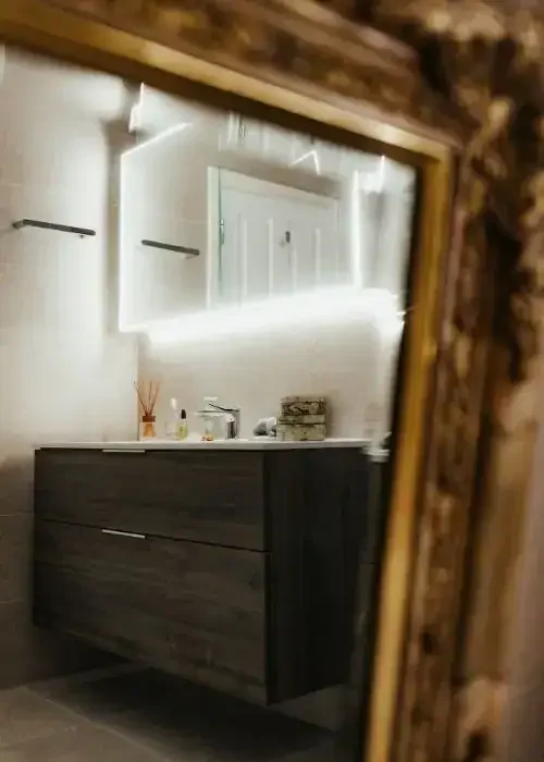 Contemporary bathroom vanity with illuminated mirror and sleek storage drawers.