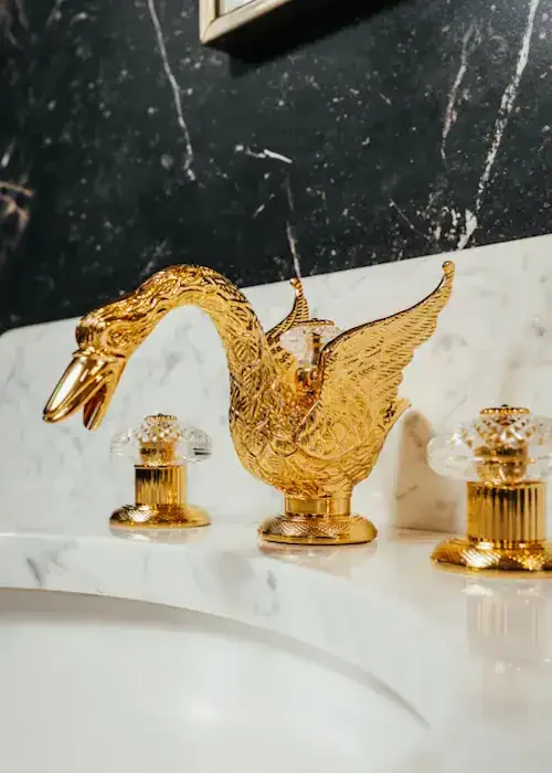Gold swan bathroom tap with decorative wings and ornate details.