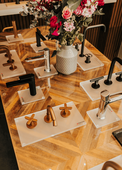 Collection of modern bathroom mixer taps displayed on a wooden table at Kallums Bathrooms.