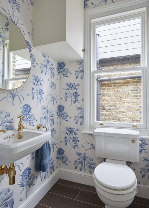 Blue floral wallpaper with white fixtures in a stylish bathroom.
