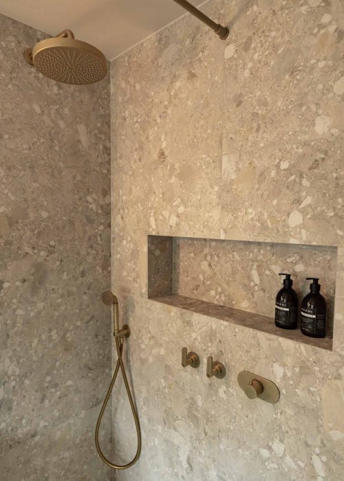 Modern walk-in shower with built-in niche and rainfall showerhead in a luxury bathroom.