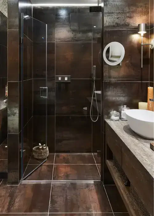 Walk-in shower with black tiles and glass enclosure, featuring a sleek design and contemporary fixtu.