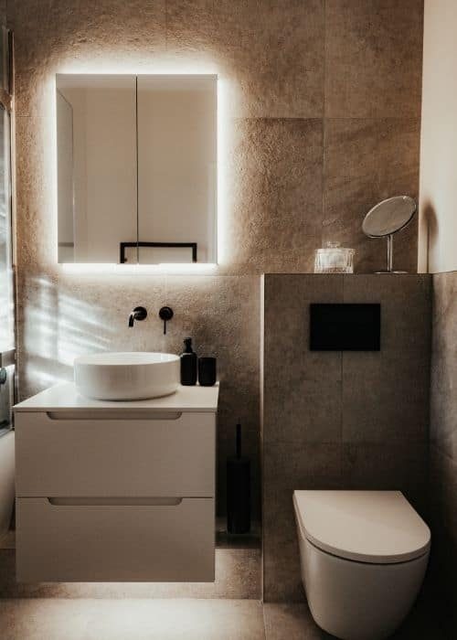 Contemporary bathroom featuring an illuminated mirror, modern sink, and stylish toilet for a minimal.