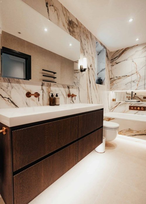 Modern bathroom with marble walls, dark wood vanity, and sleek fixtures.