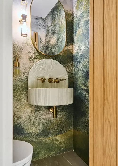 Wall-mounted bathroom sink with brass fixtures and large mirror.