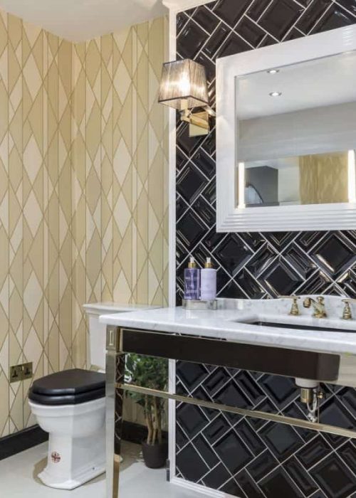 Elegant bathroom with a marble sink, black and gold accents, geometric wall patterns, and a decorative pineapple on a shelf.