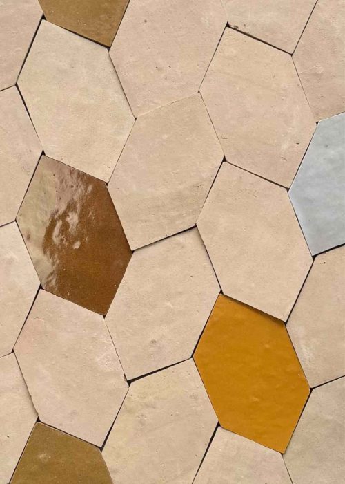 Close-up of hexagonal bathroom tiles in beige, brown, and mustard shades.