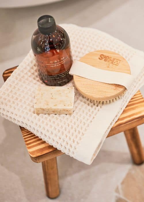 Bathroom accessories including soap, brush, and bottle on a wooden stool.