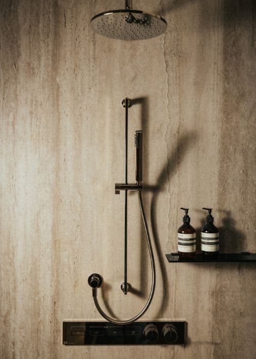 Modern walk-in shower with rainfall head and sleek black fixtures in a minimalist bathroom.