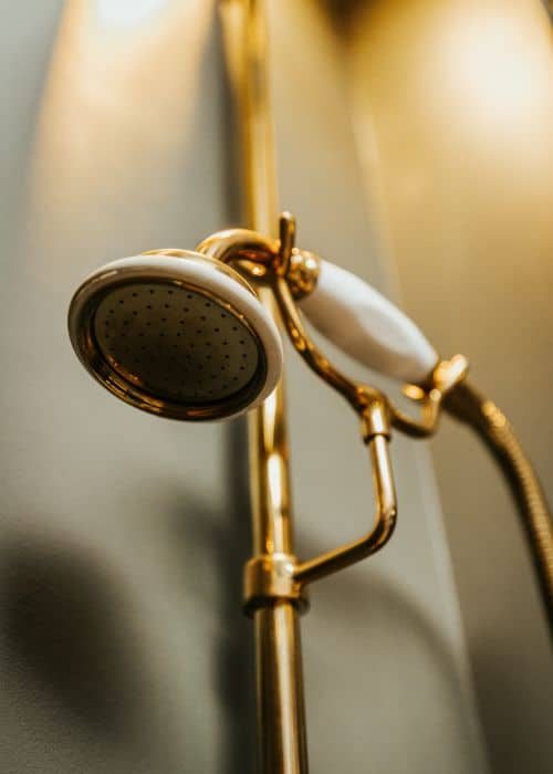 Close-up of a luxurious gold showerhead in a modern bathroom setting.