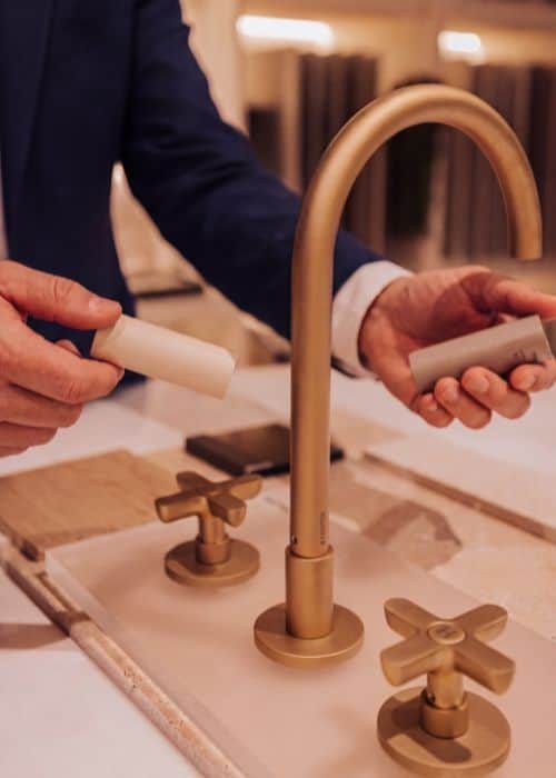 Person installing a modern gold kitchen tap with two handles in a stylish kitchen.