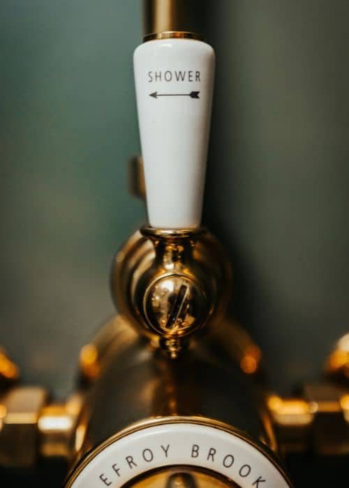 Elegant gold and white shower control with 'Shower' label and arrow.