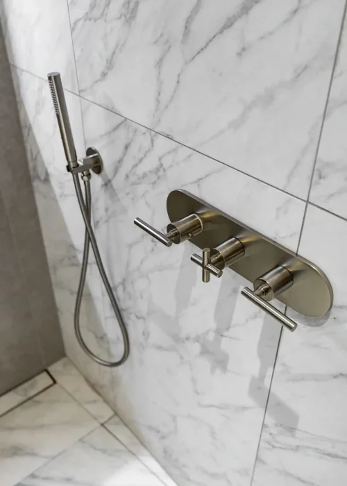Modern marble bathroom shower with sleek fixtures and handheld showerhead.