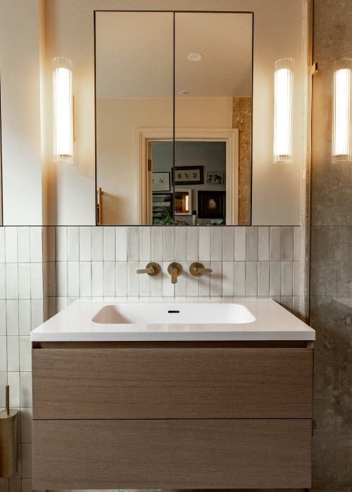 Modern bathroom vanity with large mirror and wall-mounted lights in a Victorian home.