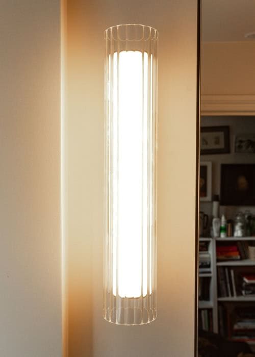 Modern vertical wall-mounted LED light fixture in a contemporary bathroom setting.