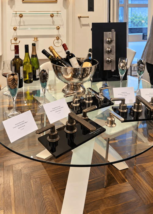Luxury bathroom display with taps, wine bottles, and decorative accessories in a modern setting.