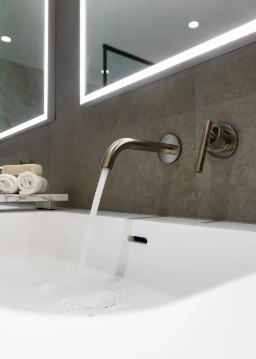 Modern bathroom with wall-mounted faucet and backlit mirror in Putney.